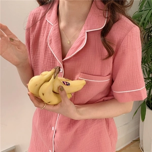 Detail of pink gauze pajamas with notch lapel and contrasting piping on the pocket