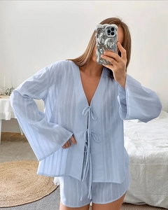 Detail of light blue cotton pajama set showing vertical striped texture and V-neck tie top