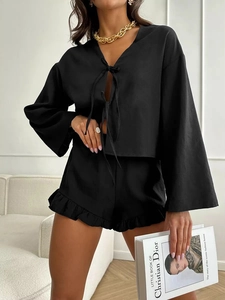 Detailed view of women's black loungewear set featuring tie-front top and ruffled hem shorts