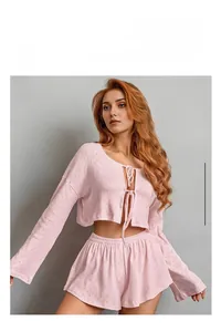 Detail of light pink knit pajamas featuring geometric jacquard texture and tie-up front