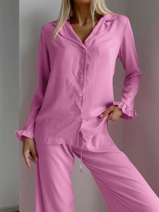 Detail of pink lounge set showing ruffle cuffs and soft long sleeve button-up texture