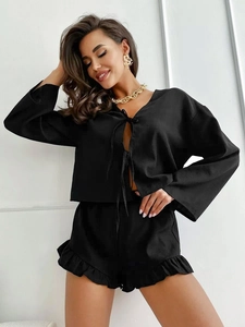 Close-up of black two-piece loungewear with tie-front top and ruffled hem shorts