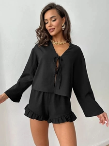 Close-up of black lace-up long sleeve top and ruffle hem shorts with gold jewelry