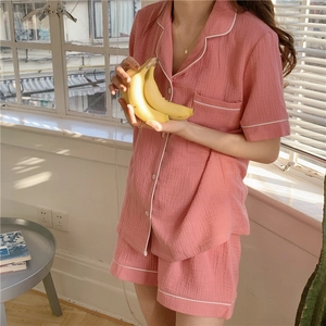 Detail of pink cotton gauze pajamas with white piping shown in a cozy home setting