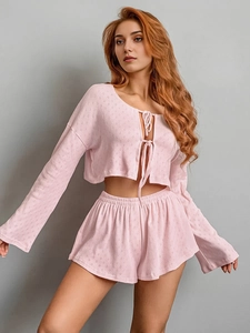 Detail of light pink knitted loungewear set featuring tie-front top and textured fabric