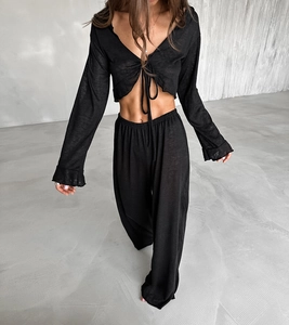 Detail view of women's black two-piece knit pajama set with V-neck top and wide-leg trousers