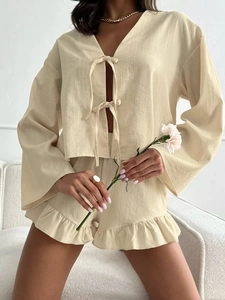 Detail of beige linen lounge set featuring tie-front cardigan and ruffled hem shorts