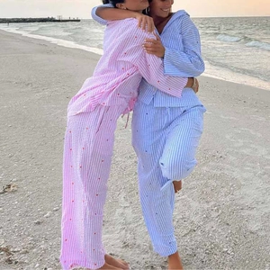 Detail of pink and blue striped pajama sets with red heart embroidery on a sandy beach