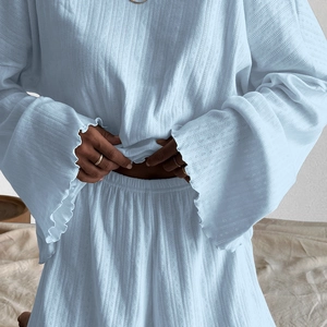 Detail von hellblauem Strick-Pyjama mit Hohlmustern und weiten Glockenärmeln