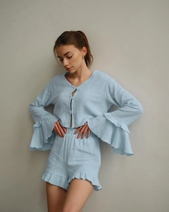 Detail of light blue cotton pajamas showing ruffled cuffs and textured button-up fabric
