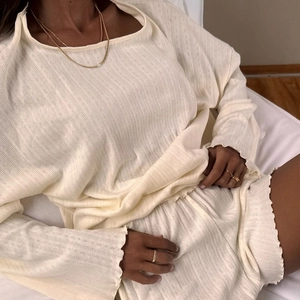 Détail du pyjama tricoté crème montrant la texture côtelée et les bords dentelés