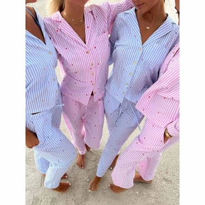 Women's striped pajama set with red heart embroidery on beach in pink and blue