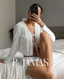 Close-up of white ribbed knit pajama set with ruffle trim and lace-up cardigan detail
