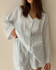 Detail eines blau gestreiften Baumwoll-Pyjama-Sets mit V-Ausschnitt und Knopfleiste oben