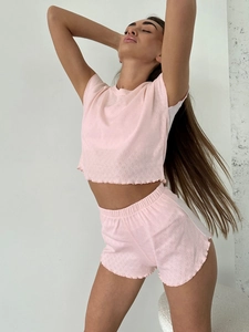 Detail of light pink knit pajamas featuring heart-shaped cutouts and wavy scalloped edges