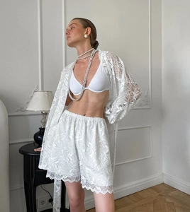 Détail du vêtement de détente en dentelle blanche avec motifs floraux et bords cils