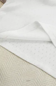 Macro shot of white pointelle knit fabric with clean double-needle stitching and soft texture
