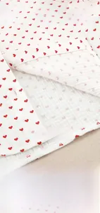 Nahaufnahme von weißem Baumwollstoff mit Herzprint zeigt feine Textur und saubere Nähte