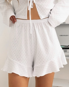 Détail du gilet blanc à nouer et short à volants avec maille ajourée en forme de cœur