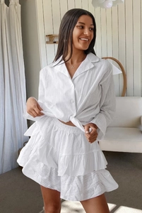Detailed macro view of white cotton pajamas showing jacquard texture and tiered ruffle skirt