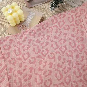 Macro detail of soft pink leopard print cotton fabric on a cozy textured bathrobe