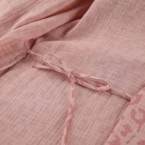 Detailed macro view of pink muslin fabric texture with leopard print and tie-up bow detail