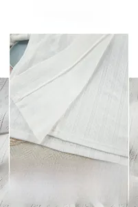 Close-up of white pointelle knit fabric texture and fine stitching detail on hem