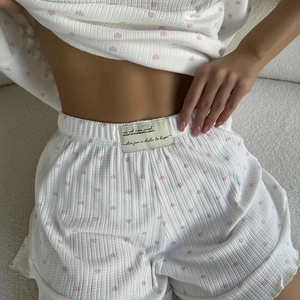 Detail of white waffle knit pajamas with pink heart print and elastic waistband logo