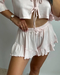 Close-up of pink knit pajamas with intricate eyelet textures and ruffled hems