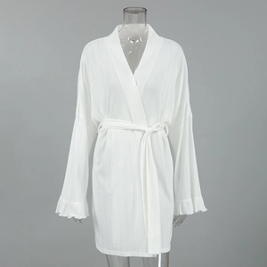 Detail of white knit robe featuring flared bell sleeves with delicate ruffle trim edges