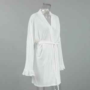 Detail view of white knit bathrobe featuring ruffled cuffs and textured ribbed fabric