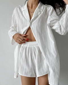 Detailed texture of white vertical stripe jacquard fabric on loose long-sleeve pajamas