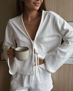Detailed view of white knit loungewear featuring hollow lace texture and bow ties