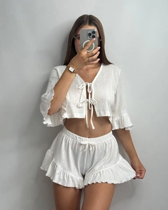 Detailed texture of white ribbed knit fabric with delicate ruffle edges and tie-up front