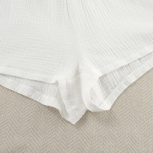 Nahaufnahme der weißen Baumwoll-Shorts mit atmungsaktiver Crinkle-Struktur und feinen Nähten