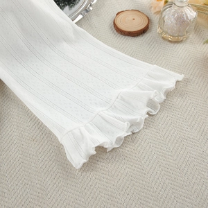 Close-up of white pointelle knit sleeve with elegant ruffled edges and ribbed texture