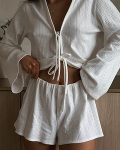 Detail of white knit loungewear featuring delicate geometric eyelet texture and tie-front