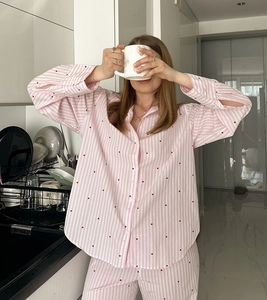 Détail de pyjama à rayures roses et blanches avec motifs cœurs rouges et boutons