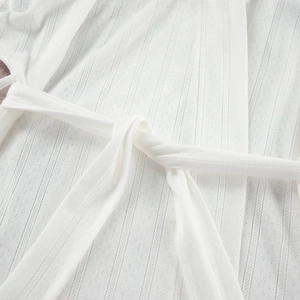Detailed view of white knit bathrobe with diamond openwork texture and waist tie