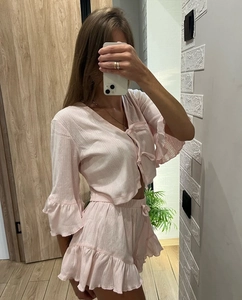 Detail of pink knit pajama set with V-neck bow ties and delicate ruffle edges