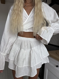 Detail of white two-piece lounge set featuring ruffle hem skirt and textured fabric