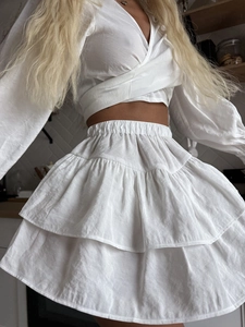 Detail of white two-piece lounge set featuring ruffles and lantern sleeves on cotton fabric