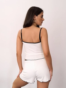 Close-up of white ribbed knit pajama set featuring black lace trim and bow details
