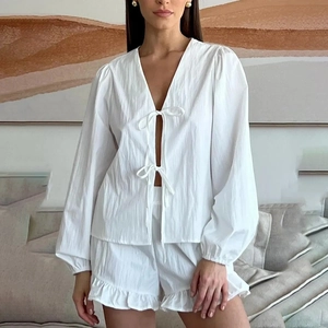 Détail d'un ensemble de détente blanc en coton avec col en V, noué et short à volants