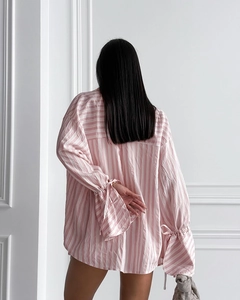 Detail of pink striped pajama shirt featuring adjustable drawstring cuffs and dropped shoulders
