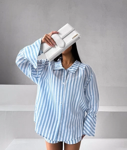 Detail of blue striped oversized pajama shirt with lapel and white buttons on stairs