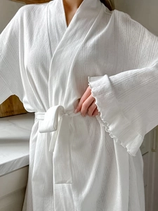 Detail of white knit robe showing delicate vertical stripes and ruffled cuffs lace texture