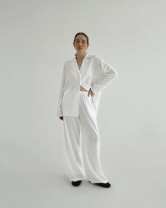 Vue de face d'un ensemble de détente en lin blanc avec pantalon large et chemise