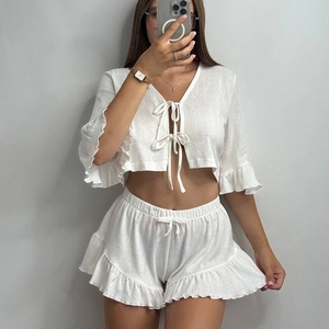 White two-piece knit pajama set with V-neck long sleeve cardigan and ruffled hem shorts