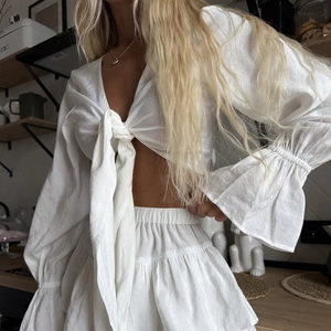 Two-piece white ruffle pajama set with tie-front lantern sleeve top and tiered skirt